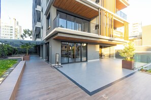 Un edificio moderno con techo plano, amplias ventanas y una zona de terraza de madera.