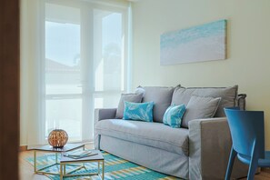 Ein Wohnzimmer mit grauem Sofa, blauen Kissen, einem Holztisch und einem blauen Sessel.