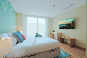 Un dormitorio con cama, mesitas de noche, una ventana, un cuadro y vistas al mar.