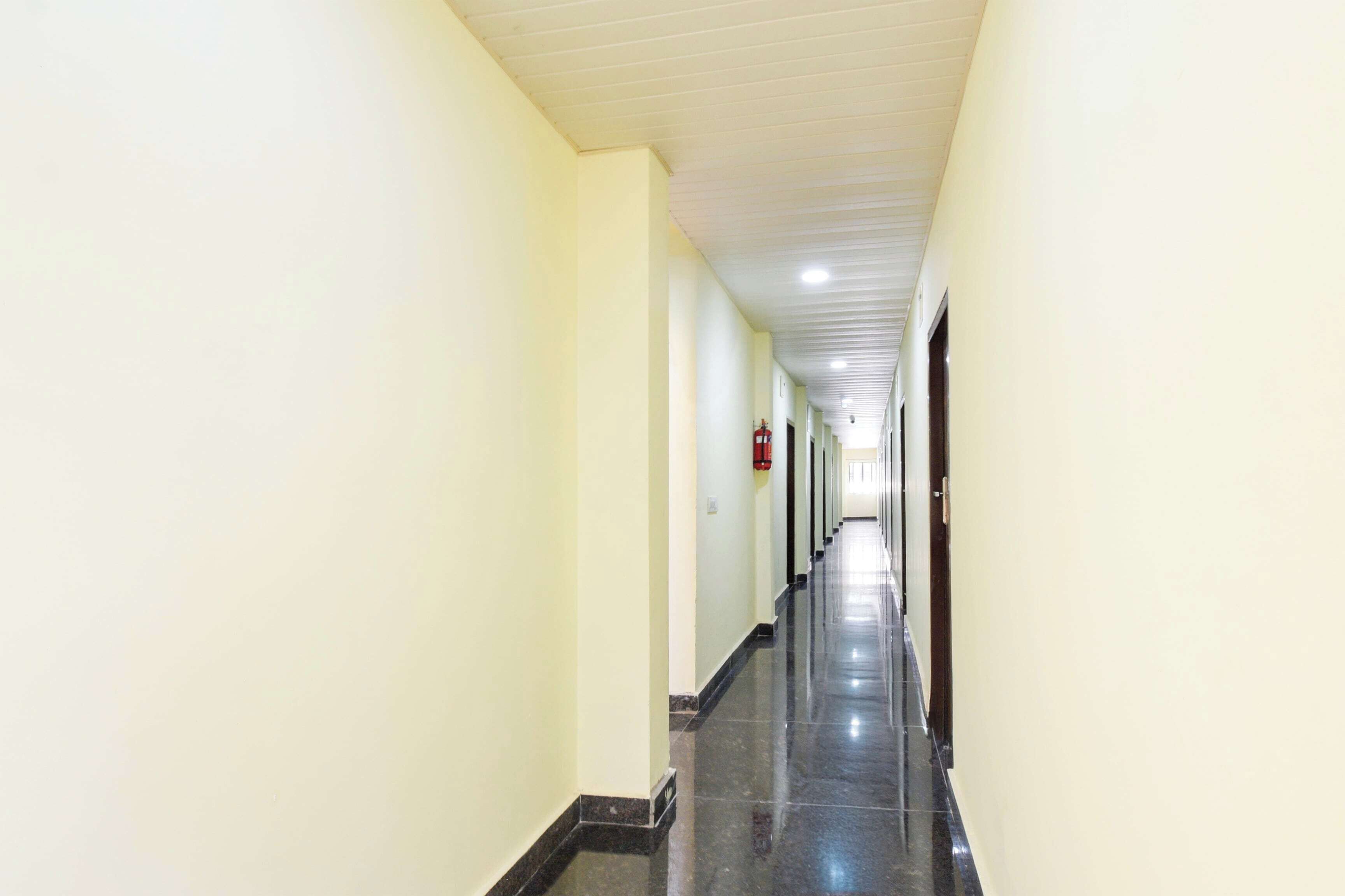 A long, narrow hallway with light-colored walls and a dark floor, leading to a door at the end.