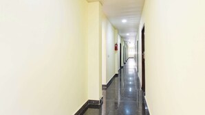 Un pasillo largo y estrecho con paredes de tonos claros y piso oscuro, que lleva a una puerta al final.