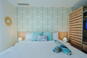 A hotel room with a large bed, two bedside tables, a wooden headboard, and a wall with a leaf pattern. - Bonsai Studio-Serenity 108 (Noord)