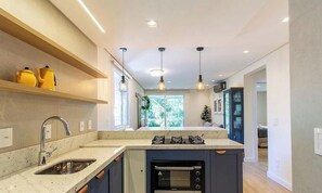 A modern kitchen with a built-in oven, a sink, and pendant lighting. - Ap Cathedral of Stone Street w/ Fireplace Mde0407 (Canela)