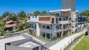 Un immeuble à plusieurs étages doté de balcons, d’une terrasse sur le toit et d’un espace paysager.