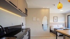 A modern kitchen with a black countertop, a built-in oven, and a wall-mounted mirror. - Studio in Condo. w/ Pool and Balcony Rso0040 (Imbituba)
