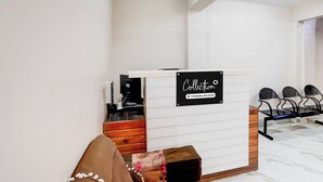 Een receptiebalie met een bord dat een afhaalservice aangeeft, een koffieapparaat en een zithoek met stoelen.