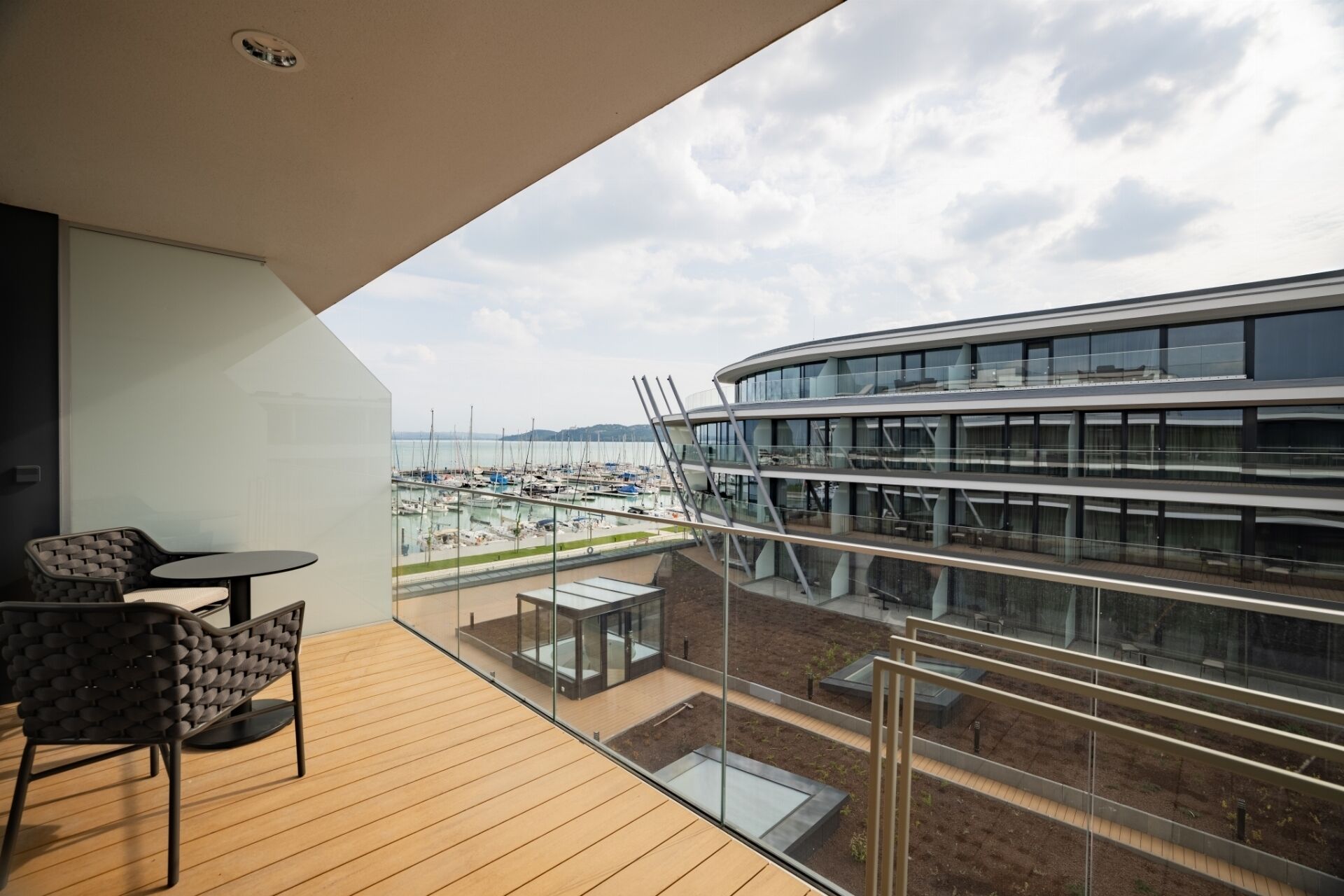 Een balkon met uitzicht op een jachthaven en een modern gebouw met meerdere verdiepingen.