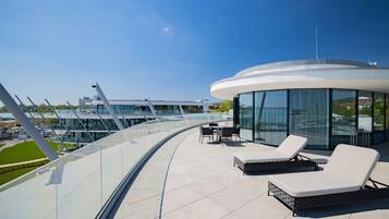 A modern outdoor lounge area with seating and a glass balustrade overlooking a marina.
