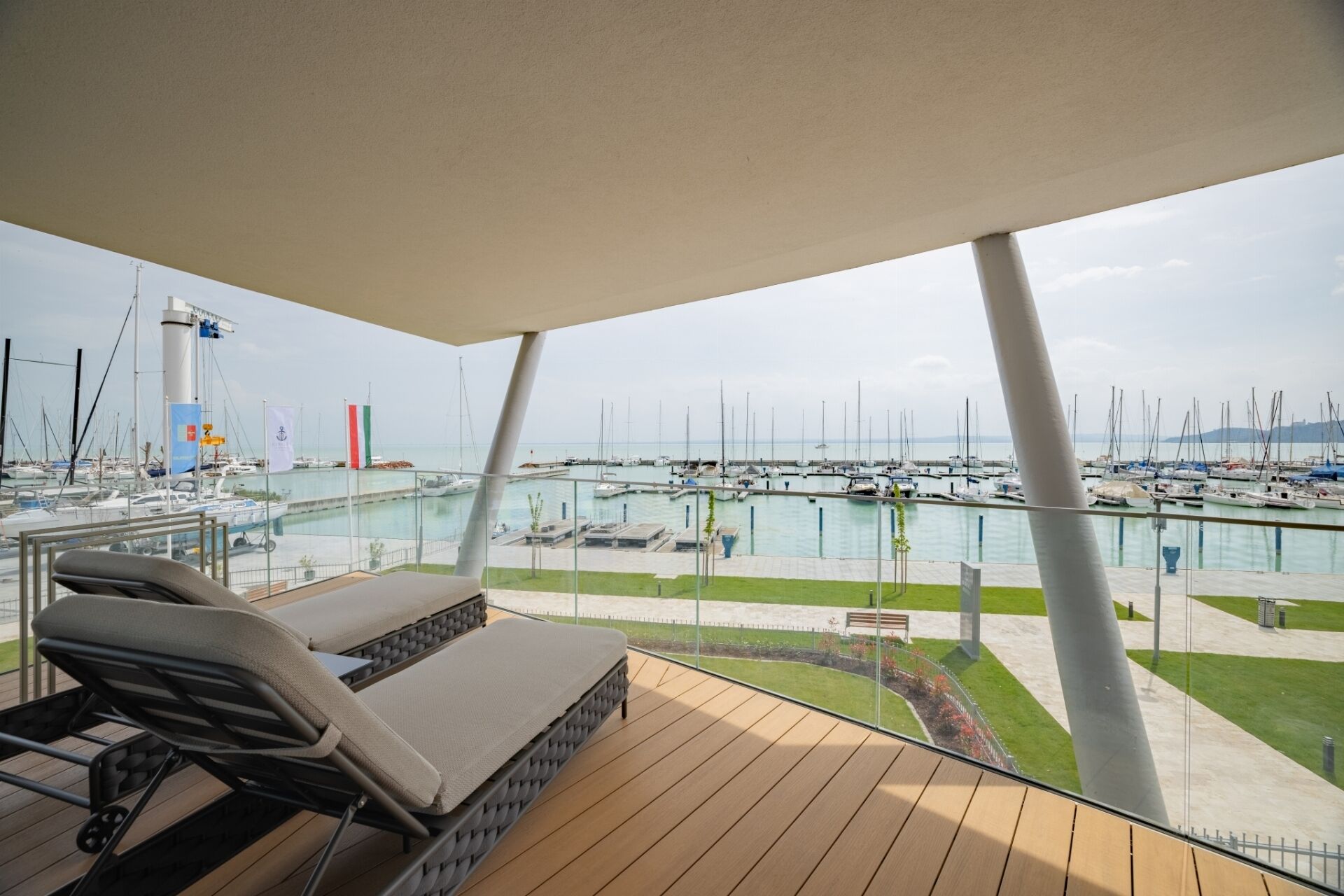 Un balcón con vista a un puerto deportivo, que incluye barcos y una bandera.
