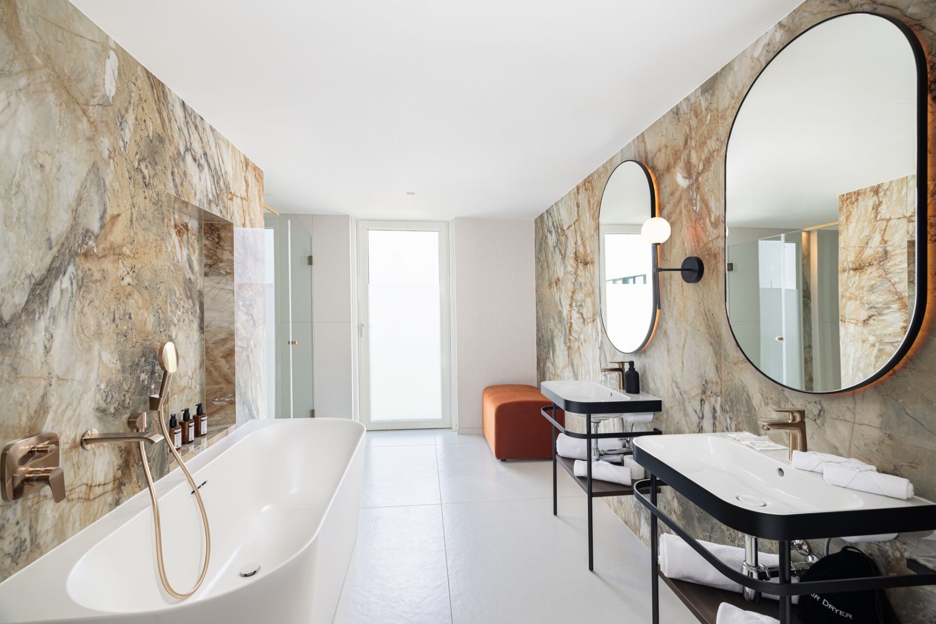 A modern bathroom with a freestanding bathtub, two sinks, and a large mirror.
