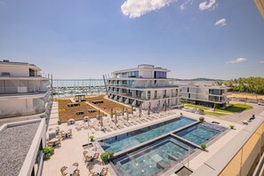 Un hotel moderno con piscina en la azotea, zona de estar al aire libre y vista al puerto deportivo.