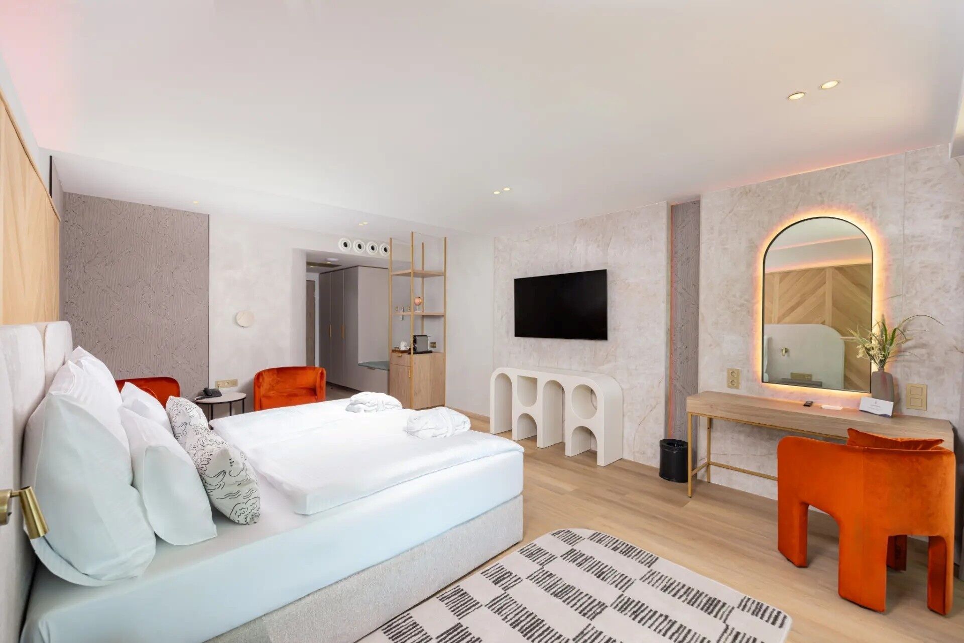 Una habitación de hotel moderna con una cama, un escritorio, una silla, un televisor y un espejo.