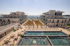 A modern hotel with a rooftop pool, outdoor seating, and a marina view.