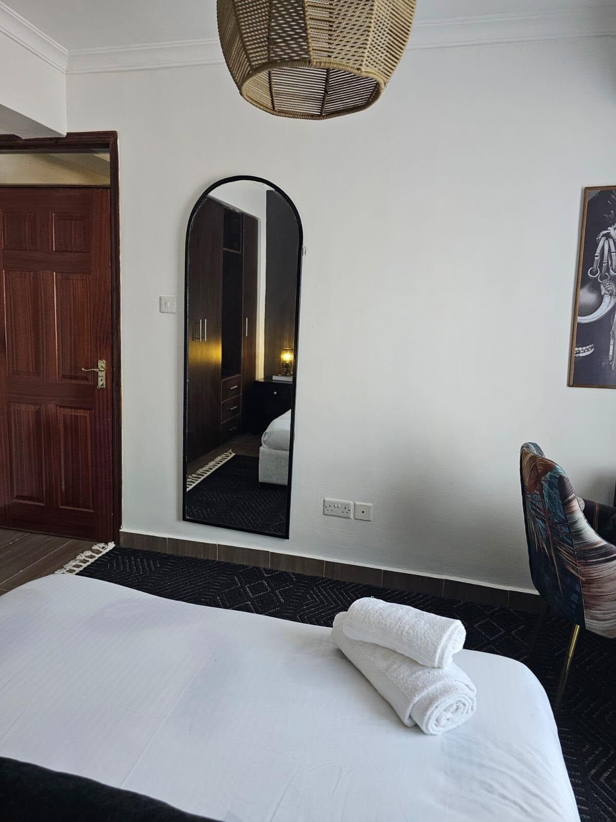 Habitación de hotel con cama, espejo, puerta y una silla.