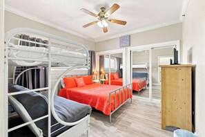 A room with bunk beds, a ceiling fan, a mirror, and a wooden cabinet. - Gulf Front Condo  at Seahorse Condos | Dog Friendly | Sleeps 9 (Pensacola Beach)