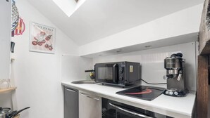A compact kitchen with a microwave, coffee machine, and a small countertop. - Charming Studio Near the Eiffel Tower (Paris)