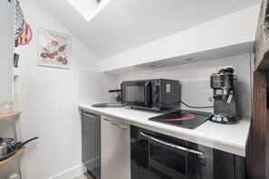 A compact kitchen with a microwave, coffee machine, and a small countertop. - Charming Studio Near the Eiffel Tower (Paris)
