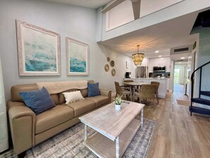 A living room with a sofa, coffee table, and artwork on the wall. - Susie's LGI - Free Ferry + Golf Cart + Pool (Placida)