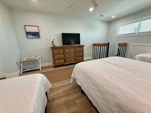 A bedroom with two beds, a television on a dresser, a window with blinds, and a picture on the wall. - Susie's LGI - Free Ferry + Golf Cart + Pool (Placida)