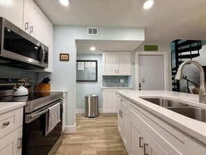 A modern kitchen with stainless steel appliances, white cabinetry, and a large island with a sink. - Susie's LGI - Free Ferry + Golf Cart + Pool (Placida)