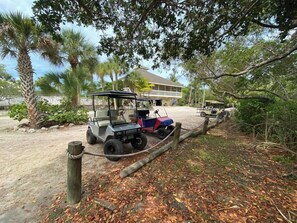 A golf cart parked near a building with a sandy area and trees. - Susie's LGI - Free Ferry + Golf Cart + Pool (Placida)