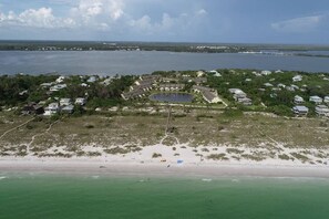 Vue aérienne d’une zone résidentielle côtière, avec des maisons, une plage et une vaste étendue d’eau.