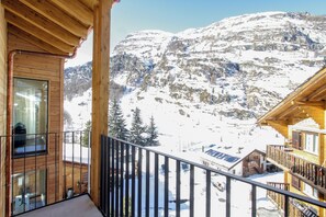 Een houten balkon met uitzicht op een met sneeuw bedekte berg.
