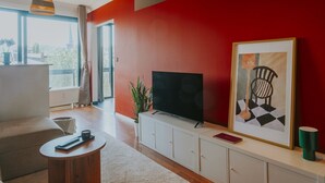 Ein modernes Wohnzimmer mit Fernseher, einem gerahmten Kunstwerk und einer Pflanze.