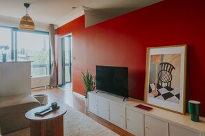 Un salon moderne avec un téléviseur, une œuvre d’art encadrée et une plante.