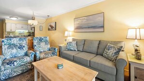 A living room with a sofa, two armchairs, a coffee table, and a painting on the wall. - Lagoon View Villa Near Beach and Tennis (Hilton Head Island)