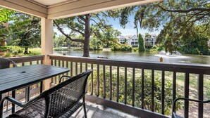 A covered outdoor area with a table and chairs, overlooking a body of water and a landscaped garden. - Lagoon View Villa Near Beach and Tennis (Hilton Head Island)