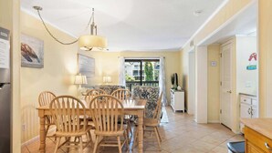 A dining area with a table and chairs, a chandelier, and a view through a window. - Lagoon View Villa Near Beach and Tennis (Hilton Head Island)