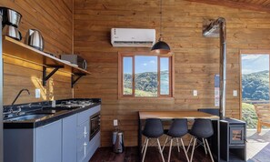 A compact kitchen with a built-in stove, a coffee maker, and a window overlooking a mountainous landscape. - Cabin With hot tub and Mountain View Vst030 (Anitapolis)
