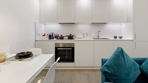 Eine moderne Küche mit weißen Schränken, einem eingebauten Backofen und einem Essbereich mit Tisch und Stühlen.