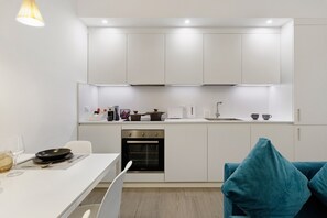 A modern kitchen with white cabinetry, a built-in oven, and a dining area with a table and chairs. - Moscova Boutique - One Apartment with Wi-Fi and Air Conditioning (Milan)