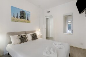 A hotel room with a bed, pillows, a bedside lamp, a painting, a window, and a mirror. - Moscova Boutique - Two Apartment with Wi-Fi and Air Conditioning (Milan)