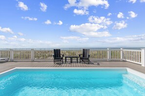Ein Pool mit Blick auf das Meer und den Strand, Liegestühle und ein Tisch.