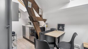 A compact kitchen with a wooden beam ceiling, a small dining table with chairs, and a blackboard with writing. - Cozy Studio - Eiffel Tower (Paris)