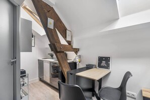 Eine gemütliche Küchenzeile mit Holzbalkendecke, einem kleinen Esstisch mit Stühlen und einer Tafel mit Schrift.