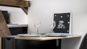 A table with two wine glasses and a framed sign with text. - Cozy Studio - Eiffel Tower (Paris)