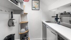 A compact kitchen with a microwave, toaster, and sink. There are shelves with glassware and decorative items. - Cozy Studio - Eiffel Tower (Paris)