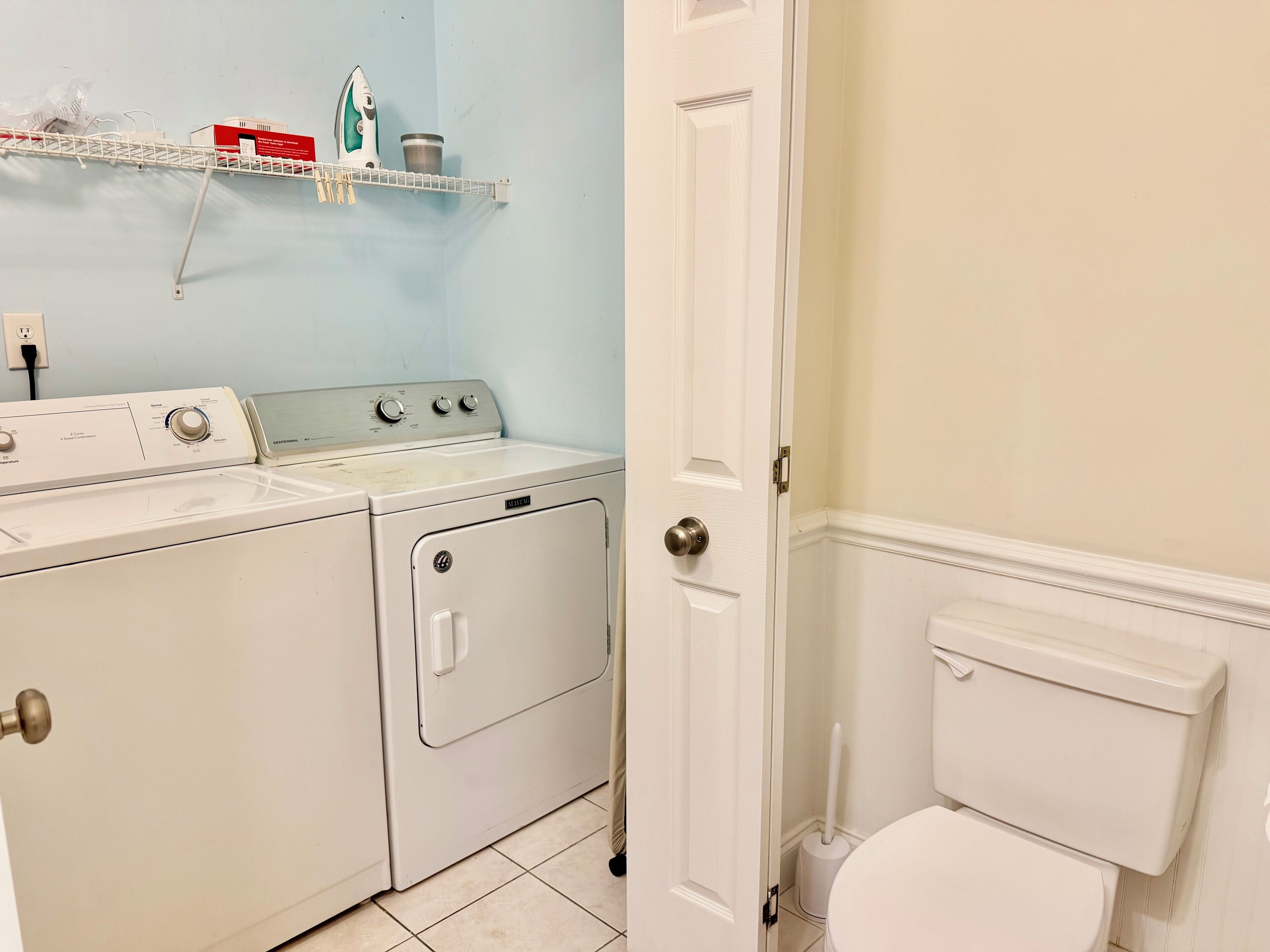 A laundry room with a washing machine, dryer, and ironing board.