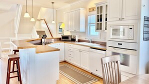 Una cocina moderna con armarios blancos, microondas integrado y una isla de madera.