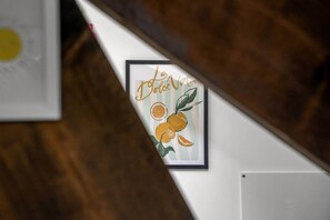 Ein gerahmtes Kunstwerk mit dem Schriftzug 'Le Dolce Vita' und Illustrationen von Orangen an einer Wand.