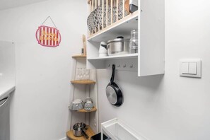 Eine Küche mit weißen Schr änken, einer hängenden Pfannenleiste und einem an der Wand montierten Lichtschalter.