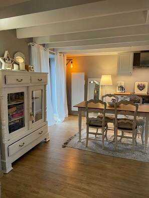 Un coin repas avec une table et des chaises en bois, un buffet blanc aux portes vitrées et une lampe.