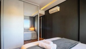 A hotel room with a bed, a wardrobe, and an air conditioning unit. - Apt. in Condo. w/ Pool & Garage Pea0410 (Florianópolis)