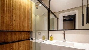 A modern bathroom with a wooden vanity, a glass shower enclosure, and a large mirror. - Apt. in Condo. w/ Pool & Garage Pea0410 (Florianópolis)