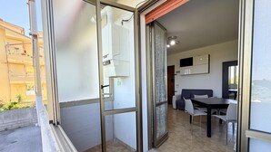 Un intérieur moderne comprenant un coin repas, une porte-fenêtre coulissante donnant sur un espace extérieur et un chauffe-eau apparent.