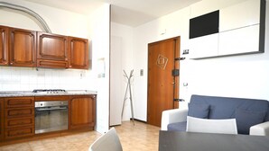 Une cuisine compacte avec des meubles en bois, un four encastré et un coin repas comprenant une table et des chaises.